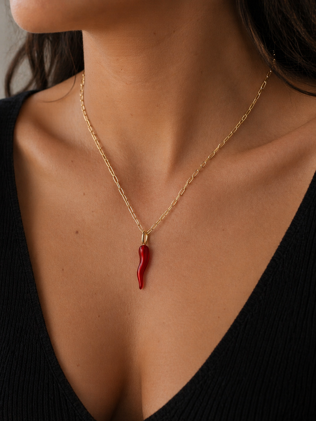 Gold necklace with a red pendant worn by a person