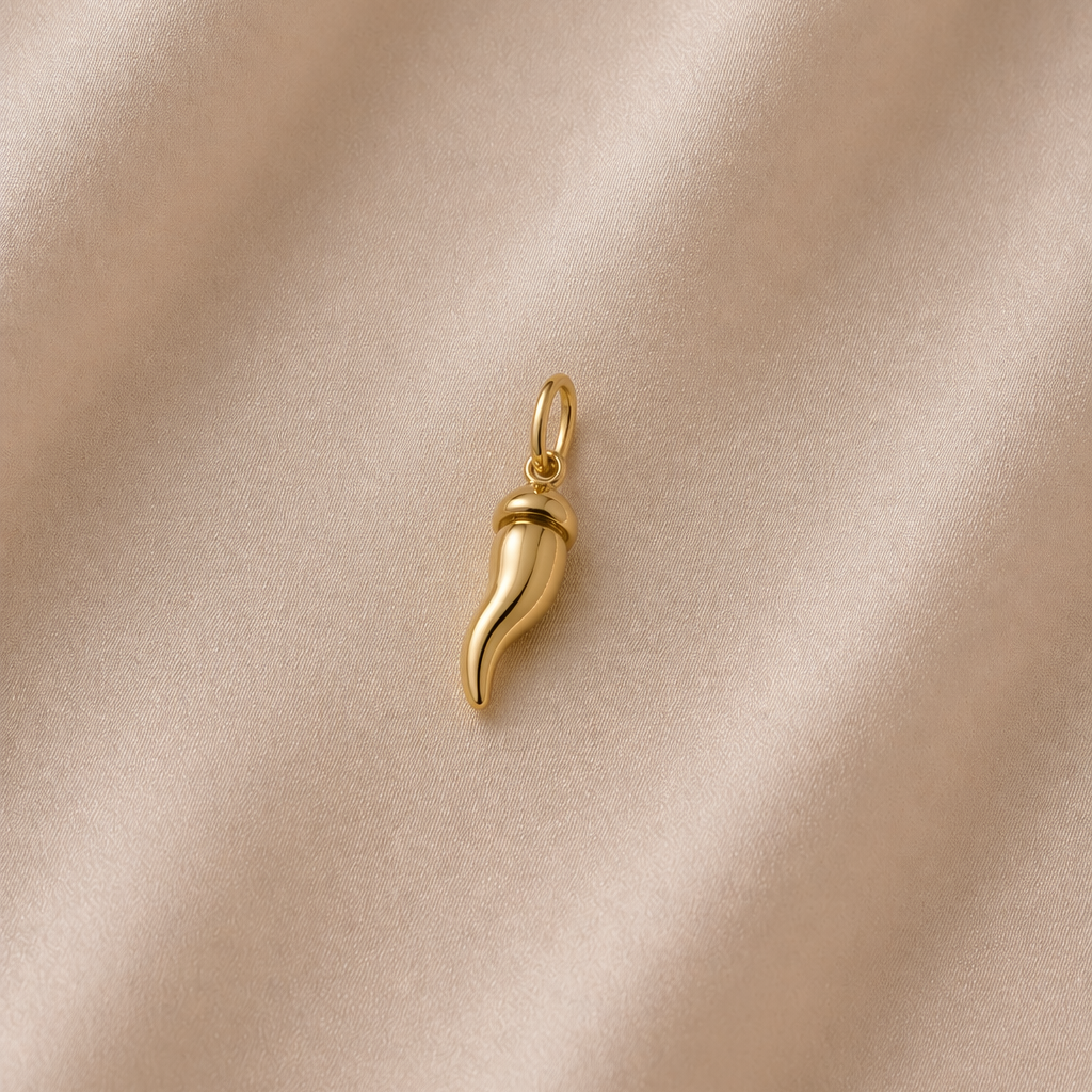 Gold horn-shaped pendant on a beige satin background