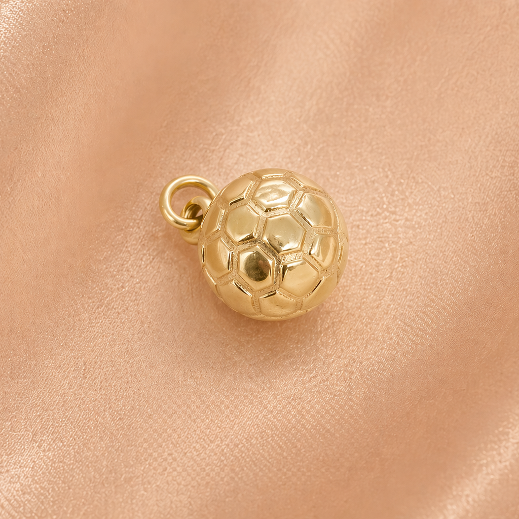 Gold soccer ball charm on a pink leather surface