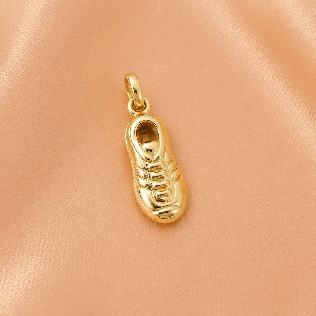 Gold shoe-shaped pendant on a peach-colored fabric background