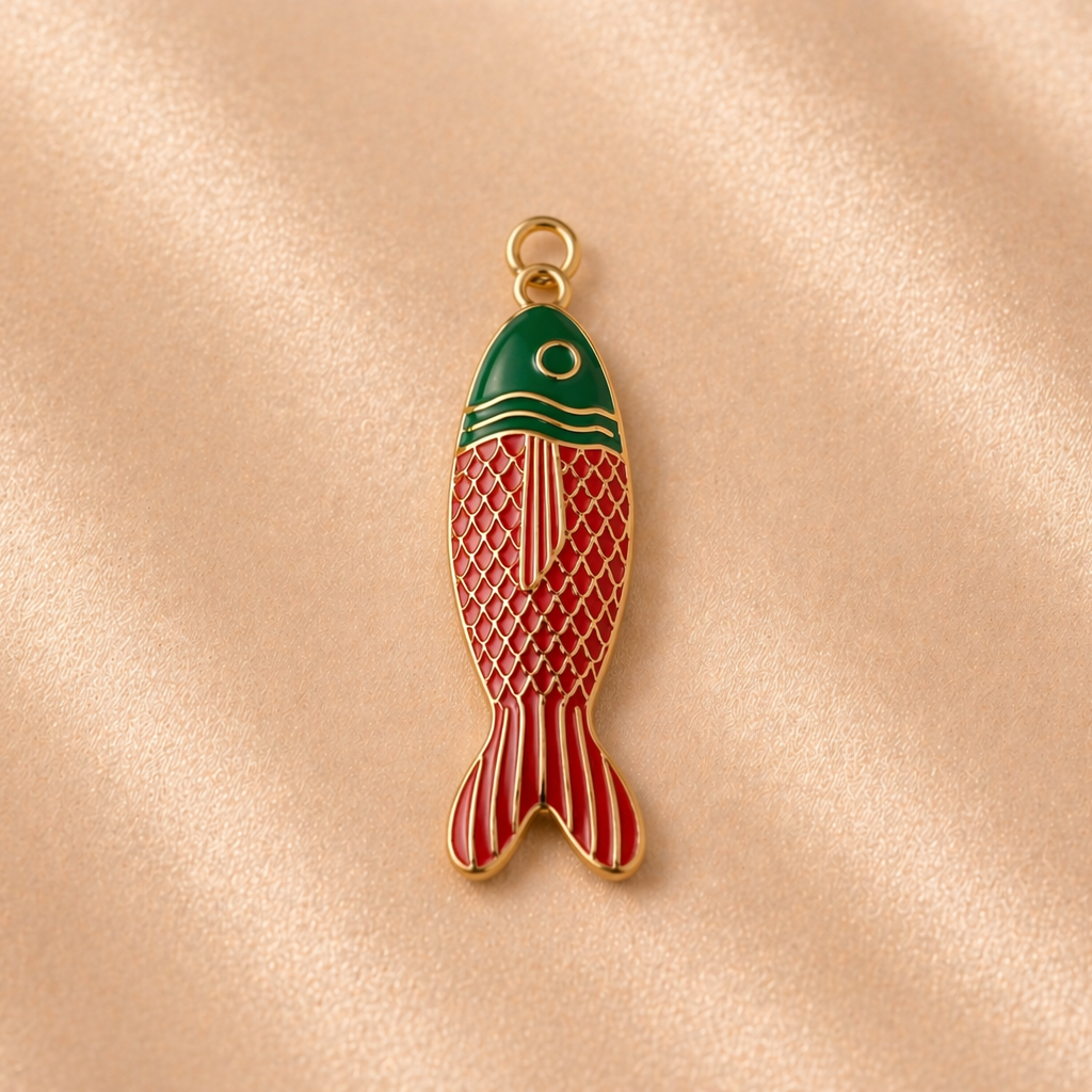 Fish-shaped pendant with green top and red body on a beige fabric background