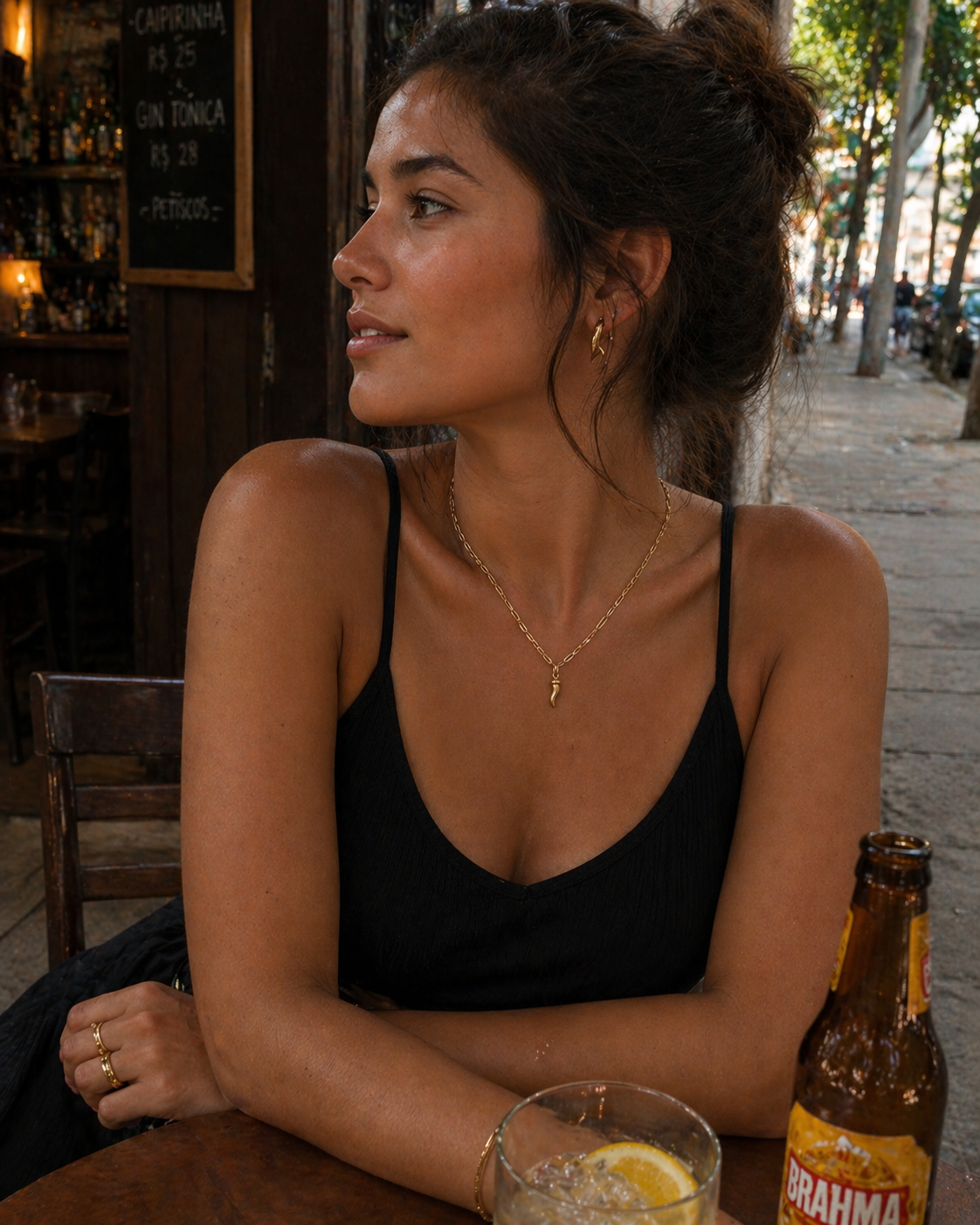 Woman sitting at a table with a bottle of Brahma beer in an outdoor setting.