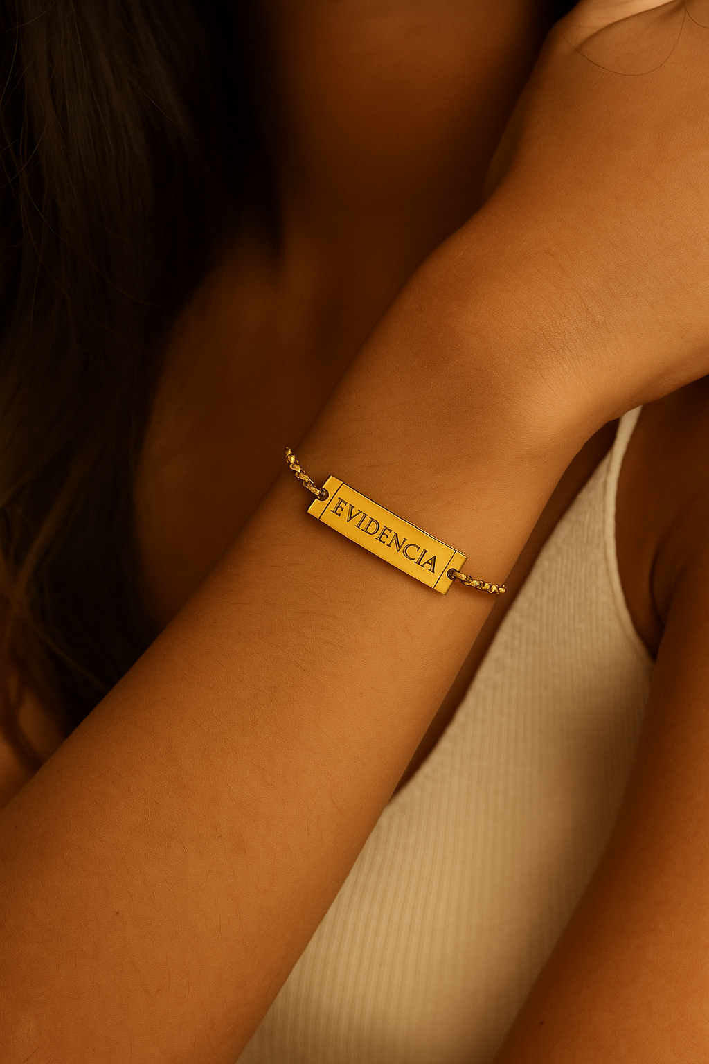 Gold bracelet with 'EVIDENCIA' on a wrist against a neutral background