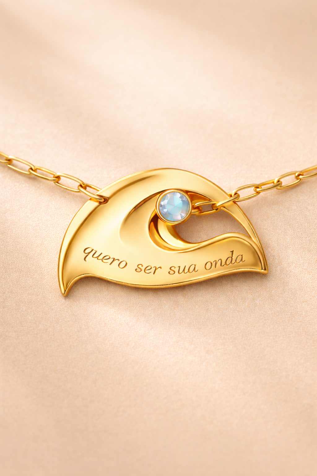 Gold necklace with a wave-shaped pendant and blue gemstone on a beige background