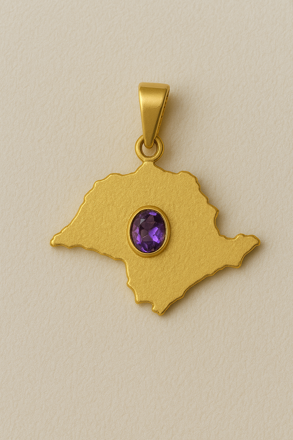 Gold pendant with a purple gemstone on a beige background