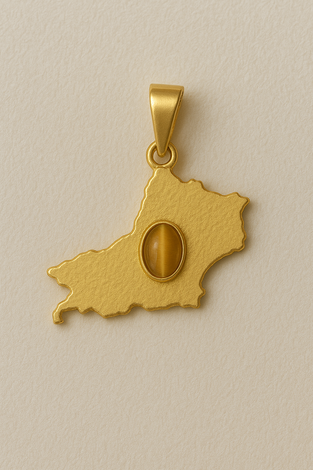 Gold pendant shaped like a map on a beige background