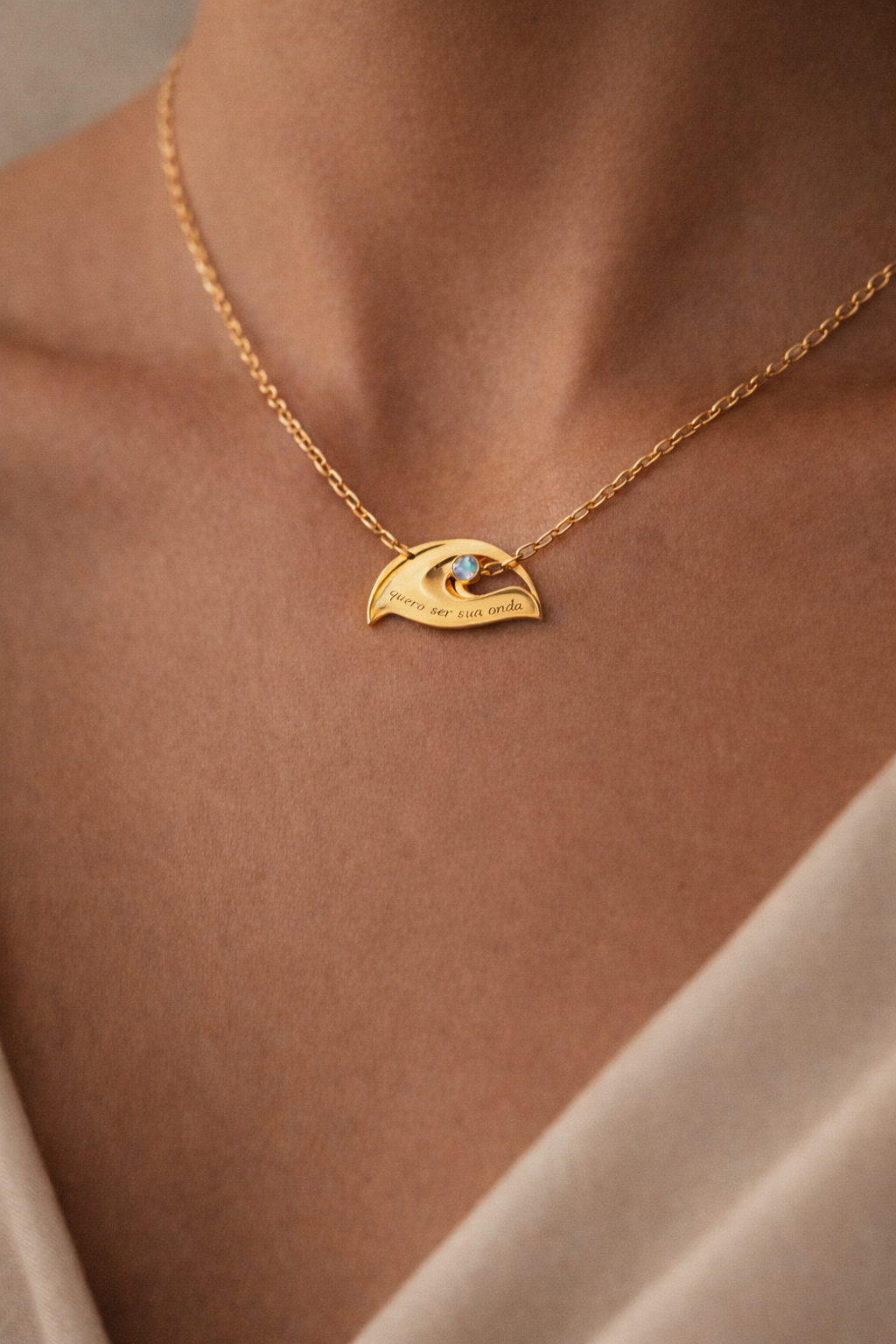 Gold necklace with a wave-shaped pendant on a person's neck